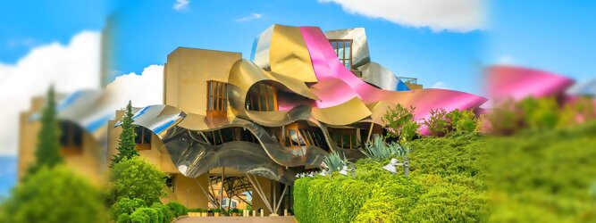 Trip Reisetipps Reisetipps - Marqués de Riscal Design Hotel, Bilbao, Elciego, Spanien. Fantastisch galaktisch, unverkennbar ein Werk von Frank O. Gehry. Inmitten idyllischer Weinberge in der Rioja Region des Baskenlandes, bezaubert das schimmernde Bauobjekt mit einer Struktur bunter, edel glänzender verflochtener Metallbänder. Glanz im Baskenland - Es muss etwas ganz Besonderes sein. Emotional, zukunftsweisend, einzigartig. Denn in dieser Region, etwa 133 km südlich von Bilbao, sind Weingüter normalerweise nicht für die Öffentlichkeit zugänglich.